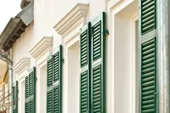 Detailansicht eines Wohnhauses im Jahrhundertwende-Stil mit grünen Fensterläden und Gesims