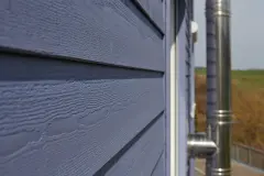 Detailansicht einer blauen Holzfassade mit vorgelegtem Kaminabzug