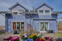 Frontalansicht eines Hauses mit zwei Gauben und hellblauer Holzfassade