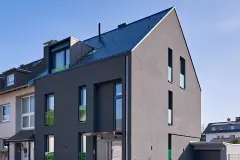 Haus mit großflächiger dunkelgrauer Putzfassade und grünen Glaselementen