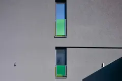 Dunkelgraue Putzfassade mit grünen Glaselementen