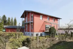 Haus mit roter Putzfassade und Garten