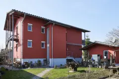 Wohnhaus mit roter Putzfassade und Metallelementen