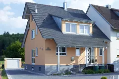 Haus mit pfirsichfarbener Putzfassade und dunkelgrauem Dach