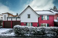 Wohnhaus mit roter Putzfassade in verschneiter Umgebung