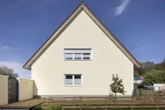 Frontale Ansicht auf ein gelbes Haus mit Satteldach
