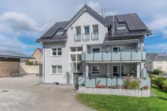 Hellgraues Zweifamilienhaus mit frisch gesäuberter und gestrichener Putzfassade