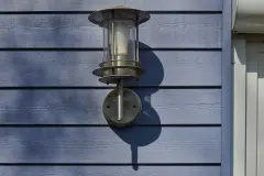 Außenlampe an himmelblauer Holzfassade
