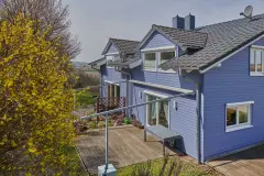 Hellblaues Haus am Waldrand