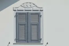 Nahansicht einer weißen Fassade mit Holzfensterläden und Dekoelementen