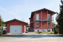 Haus mit rostroter Putzfassade und Metallelementen