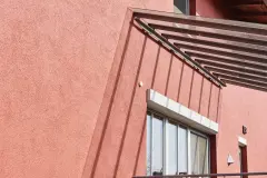Rostrote Fassade mit Vordach aus Glas