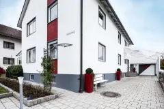 Wohnhaus mit weißer Putzfassade und rotem Dekostreifen