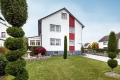 Vorgarten mit Bäumen in Formschnitt vor einem frisch gestrichenem Haus