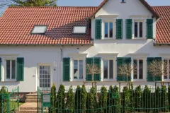 Haus mit weißer Putzfassade und grünen Fensterläden