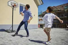 Vater und Sohn spielen Basketball auf dem Vorplatz