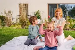 Familie spielt im Garten vor der nachhaltigen Fassade des Hauses.
