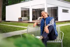 Fröhliche Frau sitzt auf der Terrasse vor ihrem Haus